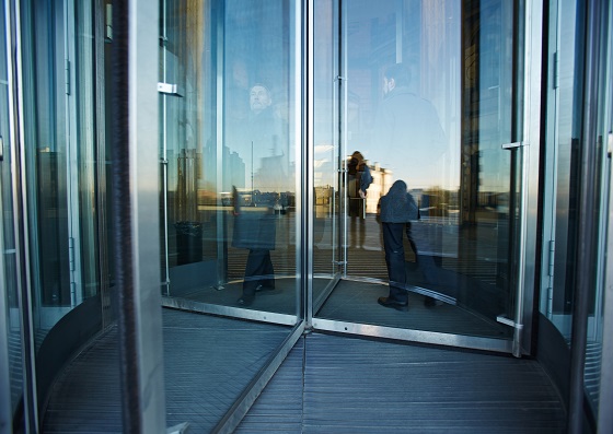 Modern men entering and leaving building through revolving door